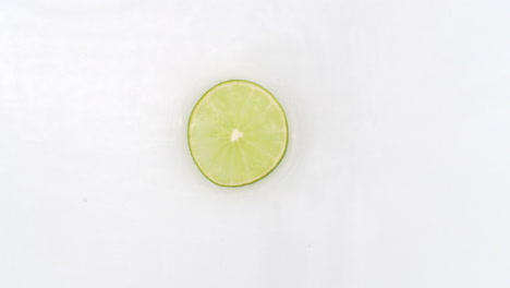 In-slow-motion-water-splashes-pour-one-lime-on-a-white-background.-Vegetarian-and-Fructorians.